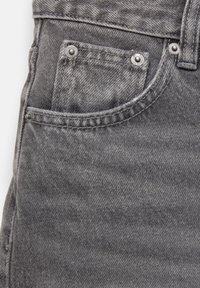 Gros plan sur un jean en denim gris usé montrant une poche avant avec des rivets métalliques et des coutures détaillées.
