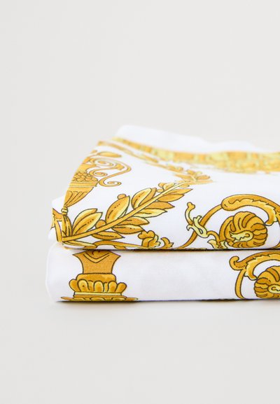 Eșarfă albă din bumbac, pliată cu grijă, cu modele florale și ornamentale aurii. Textură netedă, cu desene vii și detaliate.