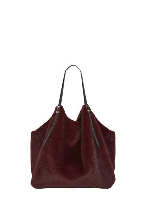Grande borsa a mano coperta da pelliccia sintetica bordeaux scuro con sottili spallacci in pelle nera e ferrature color oro.