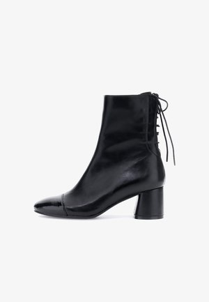 Stivale alla caviglia in pelle nera con tacco a blocco, punta arrotondata e dettagli con lacci sul retro.