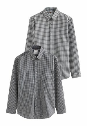 Twee longsleeve overhemden met zwart-witte ruitpatronen. Het bovenste overhemd heeft een groter ruitpatroon, terwijl het onderste overhemd een kleiner ruitpatroon heeft.
