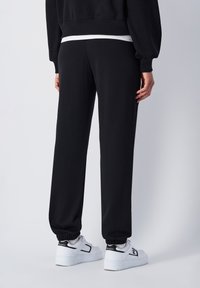 Champion ELASTIC CUFF SCRIPT SHOP - Pantalon de survêtement - black