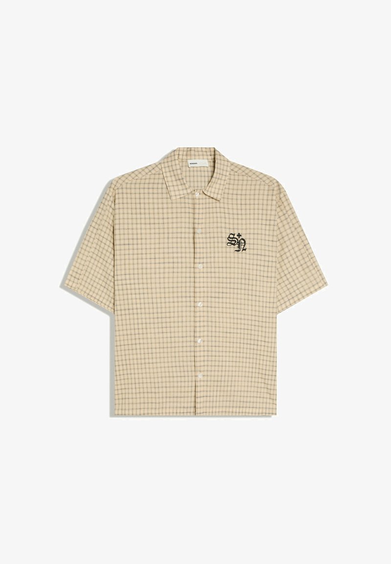 Chemise beige à manches courtes avec boutons, motif à fines carreaux marron et lettres brodées noires "SN" sur la poitrine gauche.