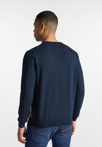 Maglione a maglia blu navy con scollo rotondo, maniche lunghe, polsini e orlo a coste. Caratterizzato da una texture liscia e un design aderente.