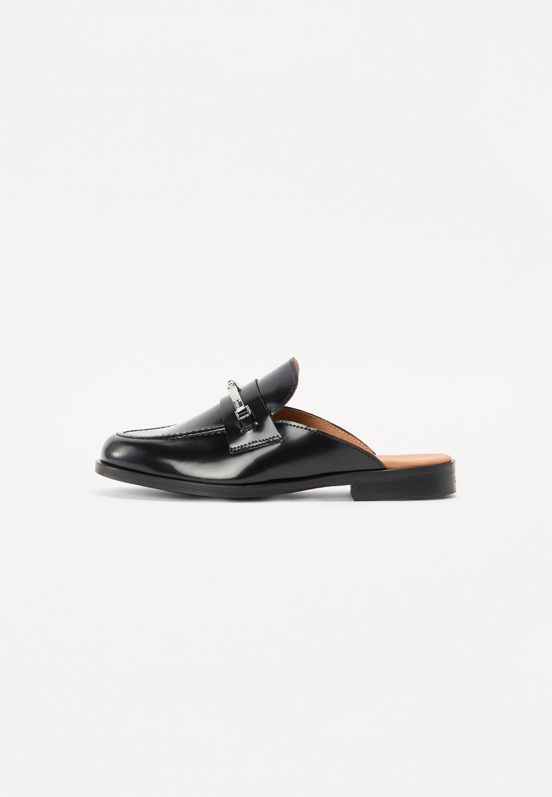 Scarpa nera in pelle senza lacci con punta arrotondata, cuciture dettagliate e un accento in metallo argentato. Suola piatta con effetto legno all'interno.