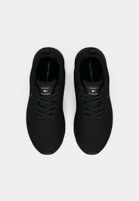 Svarta sportiga sneakers med texturerad yta och snörning. Har en logotyp på tungan och gröna innersulor. Lättviktsdesign.