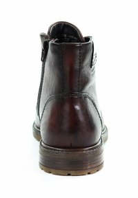 Brązowy skórzany botek sięgający kostki z gładką fakturą, bocznym zamkiem błyskawicznym oraz solidną gumową podeszwą z delikatnymi wzorami bieżnika.