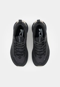 Black athletic shoes with mesh fabric, reflective laces, and a textured sole. Features a grey accent near the toe and a logo on the tongue.