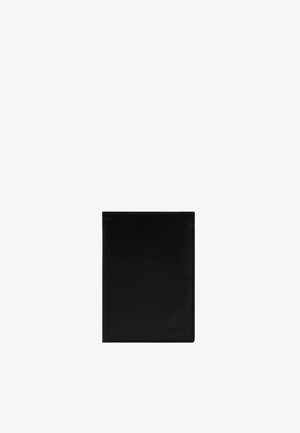 Porte-passeport en cuir noir avec un logo discrètement embossé dans le coin inférieur droit, design épuré, forme rectangulaire, fermé.