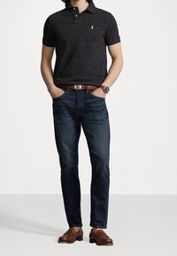 Black short-sleeve polo shirt with a logo, dark blue jeans, brown leather belt, and brown loafers. Casual outfit with a classic fit.
