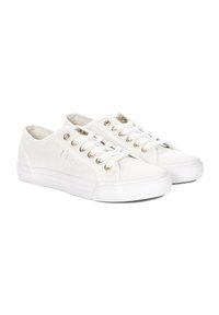 Para niskich białych trampków z płócienka z białymi gumowymi podeszwami i białymi sznurówkami przeplecionymi przez metaliczne złote oczka.