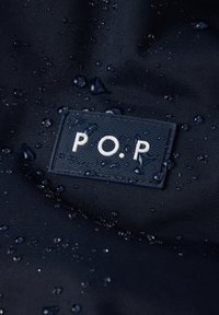 Marine stof med synlige vanddråber og et tekstureret mærke med "P.O.R." i hvidt.