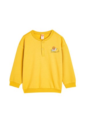 Sudadera amarilla con cuello abotonado, textura acanalada en las mangas y un gráfico de un león con el texto "BUEN DÍA RAYADO".