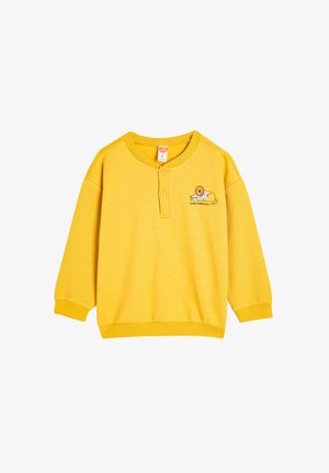 Geel sweatshirt met een knoopsluiting bij de kraag, geribbelde textuur op de mouwen en een leeuwengrafiek met de tekst "GOEDE GESTREEPTE DAG."