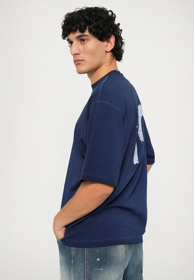 Mørkeblå t-skjorte med korte ermer som har et stort hvitt grafisk motiv på baksiden, laget av myk bomull med en avslappet passform og rund hals.