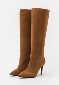 Bruine suède over-the-knee laarzen met een puntige neus en naaldhakken, voorzien van een gladde, zachte textuur en een aansluitend ontwerp.