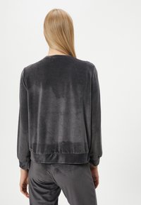 Harmaa velour-neule pyöreällä pääntiellä, ribbed hihansuilla ja helmoilla, joissa on sileä rakenne ja hienovarainen kiilto. Takakuvassa näkyy rento istuvuus.