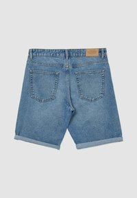 Shorts en denim bleu clair avec un ourlet roulé, comportant deux poches arrière et une étiquette beige au niveau de la taille. Coupe standard.