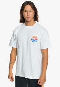 White cotton t-shirt featuring a colorful graphic with waves, a mountain, and a sun on the left chest. Relaxed fit and short sleeves.