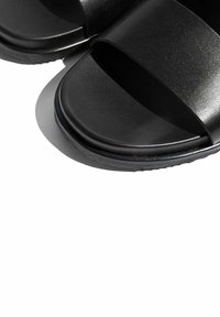 Crne sandale za klizanje s širokim, teksturiranim remenom i glatkim đonom. Čini se da je materijal sintetički s mat završnom obradom.