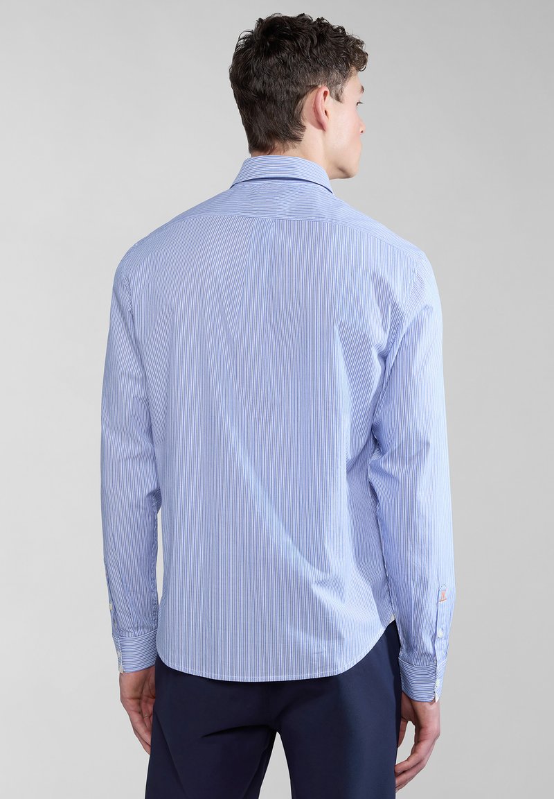 Jasnoniebieska i biała w pasiaki koszula z długim rękawem, uszyta z tkaniny w rozchodzie, z kołnierzykiem zapinanym na guziki i zaokrąglonym dołem. Widoczne guziki przy mankietach.