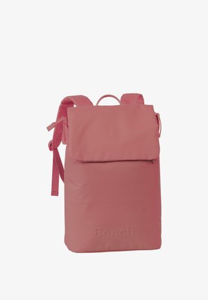 Rosa Rucksack aus weichem Material mit einem Klappenverschluss, verstellbaren Trägern und einem Oberhandgriff. Besitzt ein geprägtes Branding auf der Vorderseite.