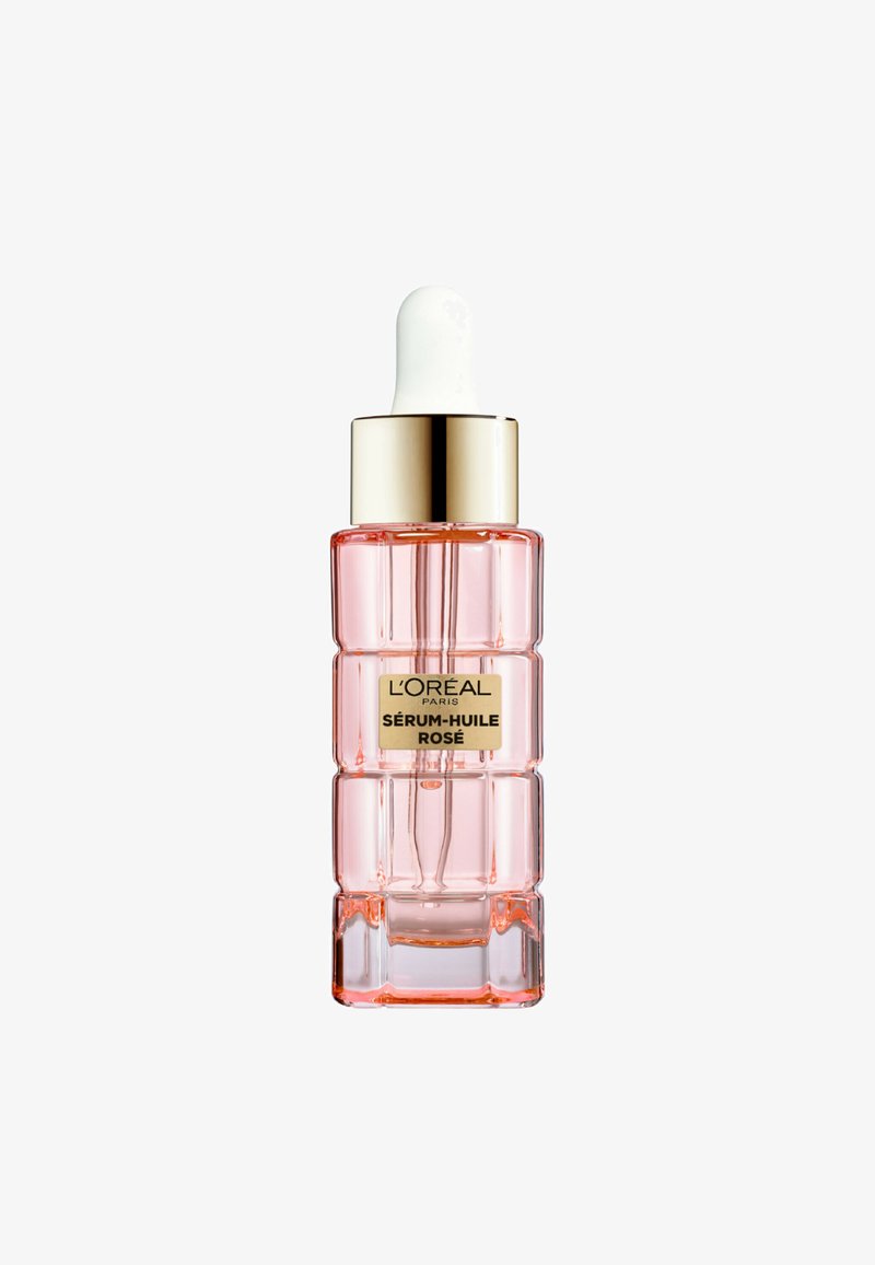 Flacon en verre transparent avec sérum facial rose, étiquette dorée portant l'inscription "L'Oréal Paris Sérum-Huile Rosé" et bouchon compte-gouttes blanc.