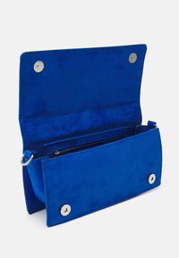 Blå mockalädersväska med en slät yta, med en dragkedjeficka och silverfärgade detaljer, designad för kompakt förvaring.