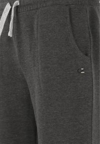 Grijze sweatpants van zacht materiaal, met een elastische tailleband, trekkoord, zijzakken en een klein geborduurd logo-detail.