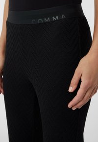 Czarne legginsy w wzór jodełki, z szerokim pasem w talii z logo "COMMA". Miękki i elastyczny materiał.