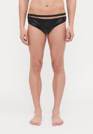 Costumi da bagno neri realizzati in un materiale lucido e morbido. Presentano un design a vita bassa e una cintura sottile. Si interrompono a metà coscia.
