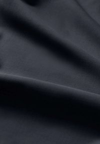 Tessuto grigio scuro con una texture liscia, caratterizzato da pieghe delicate e una finitura opaca. Non sono presenti motivi o hardware visibili.