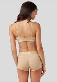 Beige treningsbh og matchende shorts med en myk tekstur. Justerbare stropper og logobånddetalj bak.