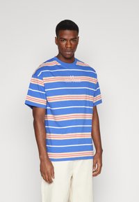 Camiseta de rayas azules con rayas horizontales naranjas y blancas, presenta el logotipo bordado "ZOO YORK", hecha de material de algodón suave.