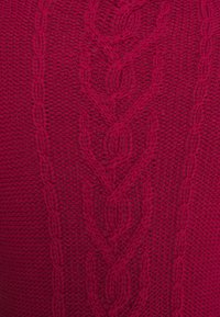 Svetr s copánkovým vzorem v hluboké červené barvě, s texturovanými vzory a žebrovanými doplňky, vyrobený z měkké tkané látky.