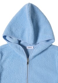 Sweat à capuche en polaire bleu clair avec une surface texturée, fermeture éclair frontale et étiquette de marque "CECIL" cousue à l'intérieur de l'encolure.