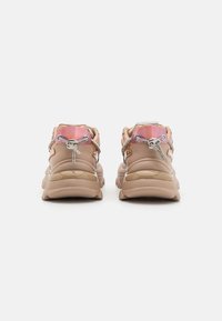 Ljust bruna sneakers med en glänsande mellansula, texturerad baksida och iriserande accenter. Har metalliska snören och en distinkt häldesign.