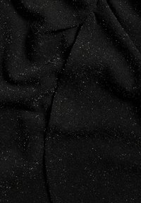 Svart tyg med en mjuk, texturerad yta, med spridda silverglitterpartiklar som skapar en skimrande effekt över materialet.