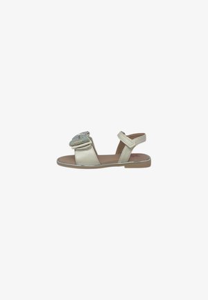 Sandalo beige piatto con cinturino alla caviglia, punta aperta e grande fiocco decorativo gioiello sulla cinghia frontale.