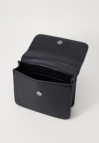 Svart plånbok i konstläder med krokodilstruktur, magnetisk tryckknapp och flera kortfack. Öppnad, vilket avslöjar inre fack.