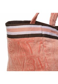 Texturierte pinke Stofftasche mit erhabenem Schriftzug, braun-weißen gestreiften Akzenten und zwei Griffen. Weiches Material mit ausgeprägten Details.