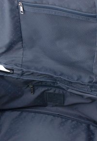 Interior de bolsa azul marino con un bolsillo de malla y un compartimento con cremallera. Tela suave con un patrón sutil y detalles de etiqueta.