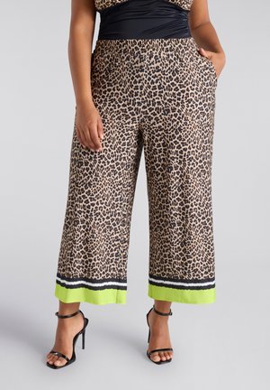 Pantalons à jambes larges en imprimé léopard beige et noir avec un ourlet bordé de vert, dotés d'une taille élastique et de poches latérales.