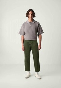 Γκρι, υφασμάτινο πόλο με κοντά μανίκια, συνδυασμένο με ελαιζιά, παντελόνια κανονικής γραμμής και λευκά αθλητικά παπούτσια. Απλός, καθαρός σχεδιασμός.