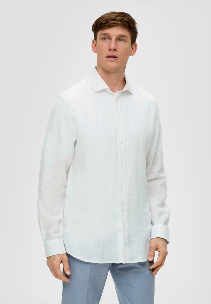 Witte long-sleeve linnen blouse met een puntige kraag, knoopsluiting vooraan en rechte zoom, gedragen met lichtblauwe broek. Zachte textuur.