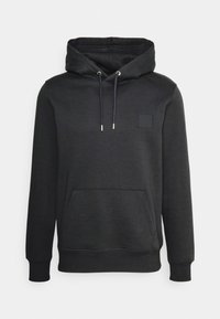 Sweatshirt à capuche noir en tissu doux, dotée d'une poche frontale, de cordons de serrage et d'un petit patch carré sur la poitrine.