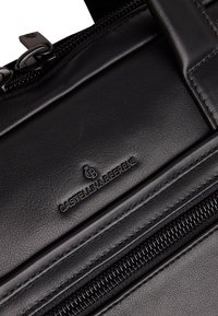 Schwarze Lederhandtasche mit strukturiertem Finish, auffälligem Reißverschluss und geprägtem Logo. Elegantes Design mit detaillierten Nähten.