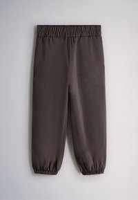 Pantalon jogger gris foncé avec taille et chevilles élastiques, étalé à plat sur une surface gris clair.