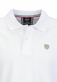 Witte polo shirt van een textuurstof, met een klassieke kraag, een knoopsluiting met twee knopen en een schildlogo op de linkerborst.
