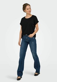 Sort kortærmet T-shirt parret med medium-vasket, lige ben jeans med subtile slidmærker og sorte flade sko.